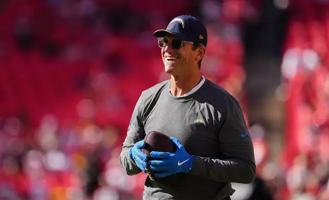 Los Angeles Chargers head coach Jim Harbaugh handles the ball as he watches warmups before an NFL football game against the Kansas City Chiefs in Kansas City, Mo., Sunday, Oct. 18, 2026. (AP Photo/Ed Zurga)