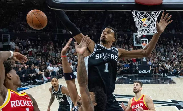 San Antonio Spurs forward/center Victor Wembanyama, center, reaches for a rebound with Houston Rockets guard Amen Thompson, left, during the first half of an NBA basketball game in Austin, Texas, Friday, Oct. 23, 2026. (AP Photo/Stephen Spillman)