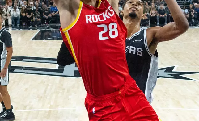Houston Rockets center Alperen Sengun (28) scores past San Antonio Spurs forward Victor Wembanyama during the first half of an NBA basketball game in Austin, Texas, Friday, Oct. 23, 2026. (AP Photo/Stephen Spillman)