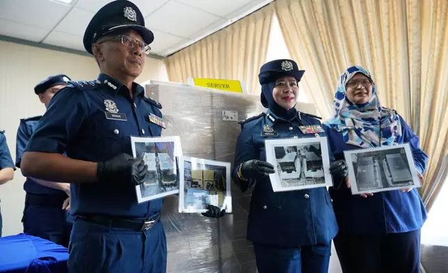 Malaysian customs officials hold photographs of seized servers containing advanced artificial intelligence chips during a press conference at its headquarters in Sepang, Malaysia, Wednesday, Oct. 28, 2026. (AP Photo/Vincent Thian)