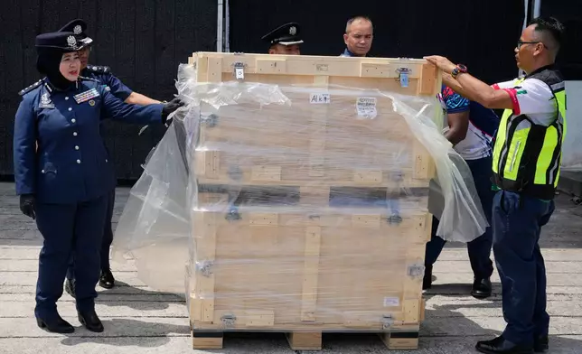 Malaysian customs personnel remove plastic wrapping from crates containing seized servers with advanced artificial intelligence chips at its headquarters in Sepang, Malaysia, Wednesday, Oct. 28, 2026. (AP Photo/Vincent Thian)