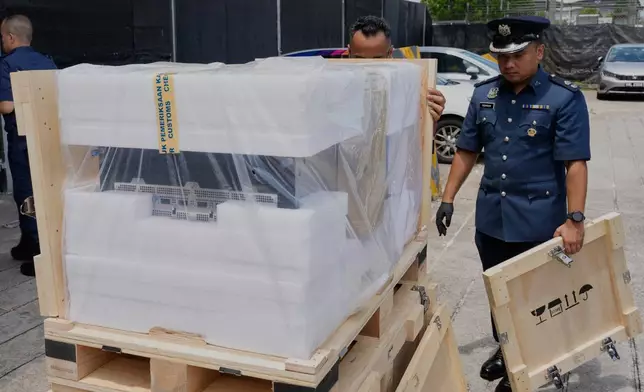 A Malaysian customs officer stands beside a seized server advanced containing artificial intelligence chips at its headquarters in Sepang, Malaysia, Wednesday, Oct. 28, 2026. (AP Photo/Vincent Thian)