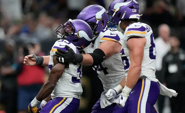 Minnesota Vikings running back Aaron Jones Sr., left, is congratulated by teammates after scoring against the New Orleans Saints during the second half of an NFL football game in New Orleans, Sunday, Oct. 11, 2026. (AP Photo/Gerald Herbert)