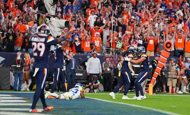 Denver Broncos safety Talanoa Hufanga, second from right, celebrates his game-ending interception with teammate linebacker Jonah Elliss, right, at the completion of an NFL football game against the Los Angeles Rams, Sunday, Sept. 27, 2026, in Denver. (AP Photo/Jack Dempsey)