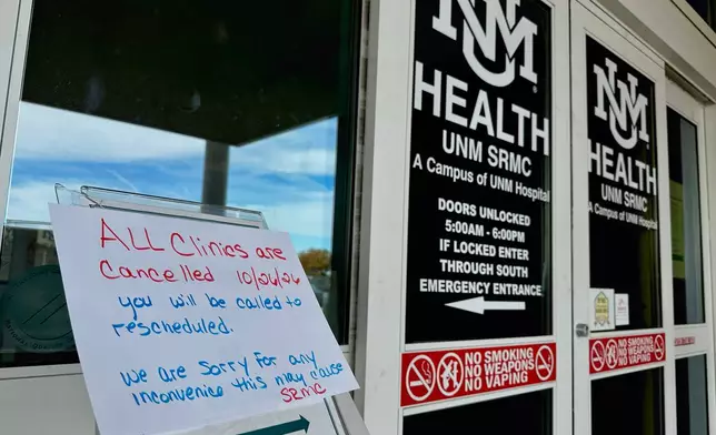 In this photo taken with a smartphone, a sign at the main entrance of the UNM Sandoval Regional Medical Center in Rio Rancho, N.M., warns visitors that clinics are closed Monday, Oct. 26, 2026. (AP Photo/Susan Montoya Bryan)