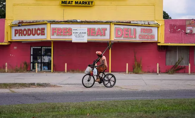 A man rides his bicycle past a closed meat market in the Scotlandville section of Baton Rouge, La., Wednesday, Sept. 16, 2026. (AP Photo/Gerald Herbert)