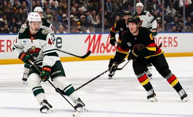 Minnesota Wild's Quinn Hughes (43) evades Vancouver Canucks' Brock Boeser (6) during the first period of an NHL hockey game, in Vancouver, British Columbia, Sunday, Oct. 25, 2026. (Jacob Mallari/The Canadian Press via AP)