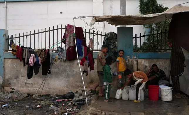 Palestinians fill plastic bottles with water at a tent camp in Deir al-Balah, Gaza Strip, Thursday, Oct. 22, 2026. (AP Photo/Abdel Kareem Hana)