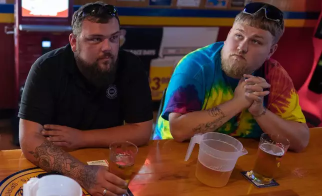 UAW Local 402 members Chaz Graham, left, and Kyle Bos, right, share a beer at Fricker's restaurant and bar in Springfield, Ohio, on Wednesday, Sept. 30, 2026, on old Navistar's last day at its Springfield plant. (AP Photo/Carolyn Kaster)