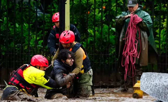 A man is pulled to safety by rescue workers after heavy rains caused flash flooding in the Las Condes district of Santiago, Chile, Thursday, Oct. 8, 2026. (AP Photo/Esteban Felix)