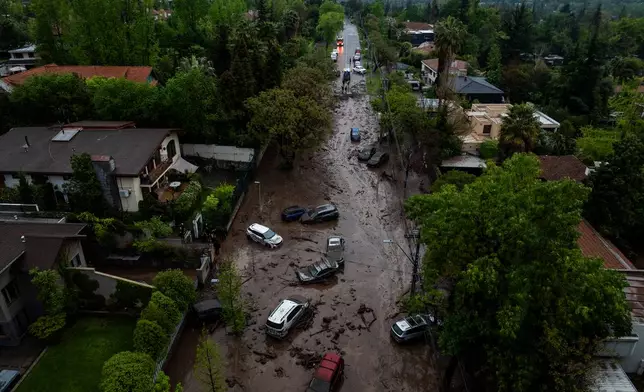 Vehicles are partially inundated in muddy floodwaters after heavy rains caused flash flooding in the Las Condes district of Santiago, Chile, Thursday, Oct. 8, 2026. (AP Photo/Esteban Felix)