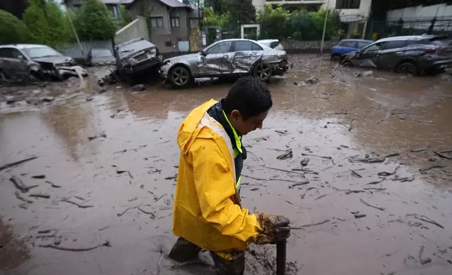 A man wades through muddy floodwaters after heavy rains caused flash flooding in the Las Condes district of Santiago, Chile, Thursday, Oct. 8, 2026. (AP Photo/Esteban Felix)