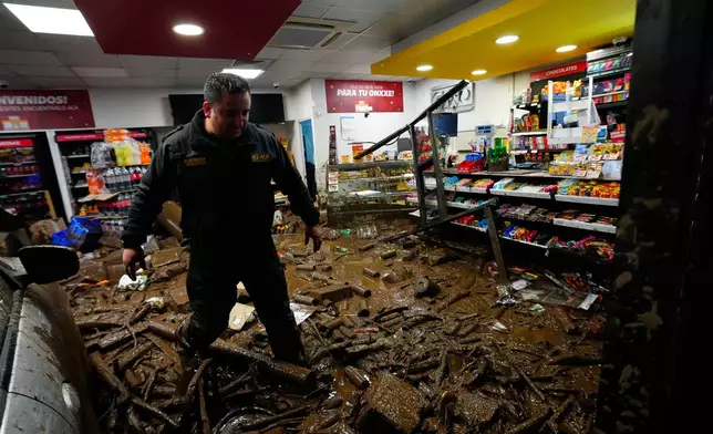 A rescue worker walks through muddy debris in a shop damaged by flash flooding caused by heavy rains in the Las Condes district of Santiago, Chile, Thursday, Oct. 8, 2026. (AP Photo/Esteban Felix)