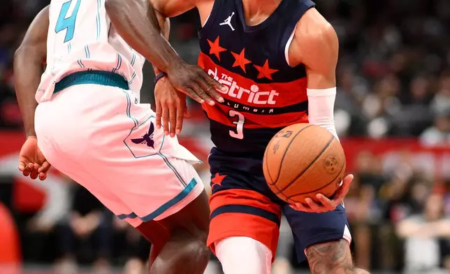 Washington Wizards guard Trae Young (3) is fouled by Charlotte Hornets guard Sion James (4) during the first half of an NBA Cup basketball game, Friday, Oct. 30, 2026, in Washington. (AP Photo/Nick Wass)