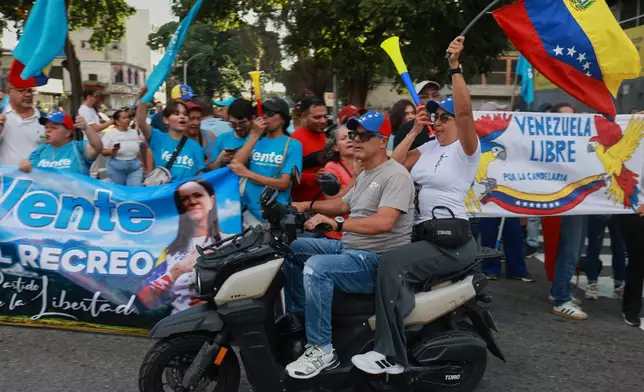 Supporters of Venezuelan opposition leader and Nobel Peace Prize laureate Maria Corina Machado rally as they await her arrival in Caracas, Venezuela, following her return to the country after months abroad, Sunday, Oct. 25, 2026. (AP Photo/Javier Campos)