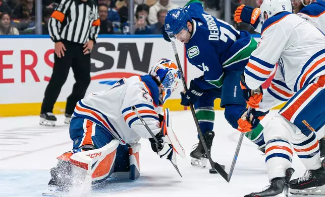 Vancouver Canucks' Jake DeBrusk (74) is stopped in close by Edmonton Oilers goalie Devon Levi (27) during the third period of an NHL hockey game in Vancouver, British Columbia, Thursday, Oct. 1, 2026. (Rich Lam/The Canadian Press via AP)