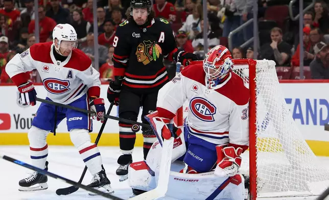 Montreal Canadiens goaltender Jacob Fowler, right, makes a save as defenseman Mike Matheson, left, and Chicago Blackhawks left wing Tyler Bertuzzi, center, watch during the second period of an NHL hockey game, Friday, Oct. 23, 2026, in Chicago. (AP Photo/Jessie Alcheh)