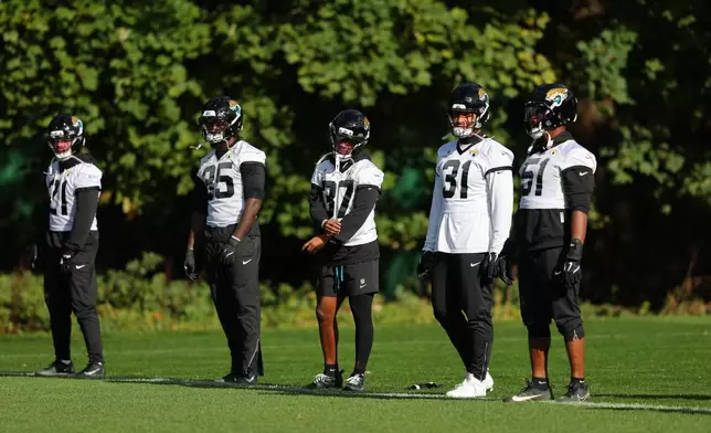 Members of the Jacksonville Jaguars wait for their drills during an NFL football practice in Hertfordshire, England, Friday, Oct. 16, 2026. (AP Photo/Adam Bettcher)