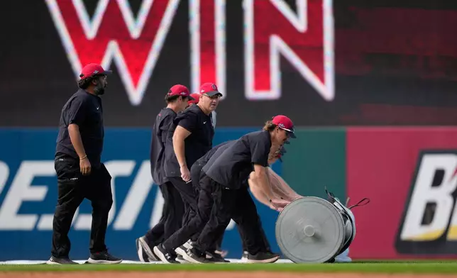 Members of the grounds crew prepare the field for weather after Game 3 of an American League Championship Series baseball game between the Cleveland Guardians and the Tampa Bay Rays in Cleveland, Thursday, Oct. 15, 2026. (AP Photo/David J. Phillip)