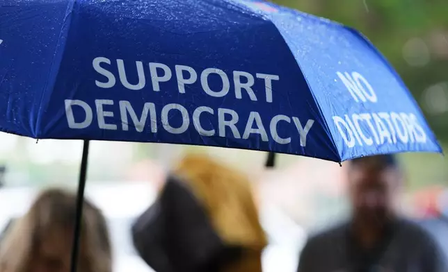 A person carries an umbrella outside a polling location during early voting in the 2026 midterm elections, Tuesday, Oct. 27, 2026, in Coral Gables, Fla. (AP Photo/Lynne Sladky)