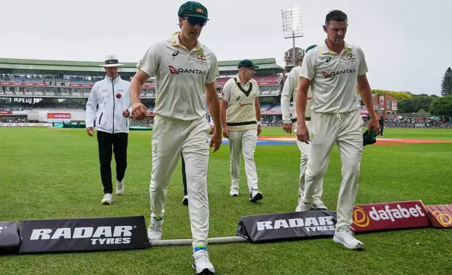 Australia's captain Pat Cummins, left, and Australia's Josh Hazlewood return to the dressing room as rain delays play on day one of the second cricket test match between South Africa and Australia, in Gqeberha, South Africa, Sunday, Oct. 18, 2026. (AP Photo/ Themba Hadebe)
