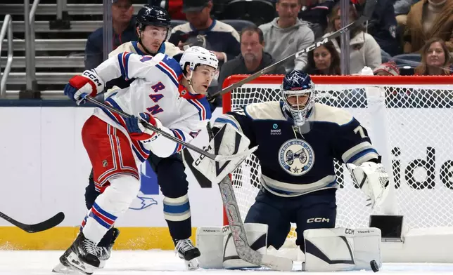 Columbus Blue Jackets goalie Jet Greaves, right, makes a stop in front of New York Rangers forward Tye Kartye, center, and Blue Jackets defenseman Zach Werenski during the second period of a NHL hockey game in Columbus, Ohio, Saturday, Oct. 17, 2026. (AP Photo/Paul Vernon)