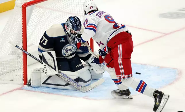 Columbus Blue Jackets goalie Jet Greaves, left, stops a shot in front of New York Rangers forward Mika Zibanejad during the third period of a NHL hockey game in Columbus, Ohio, Saturday, Oct. 17, 2026. (AP Photo/Paul Vernon)