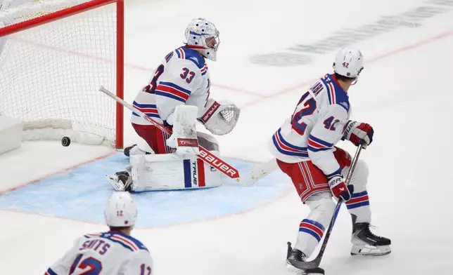 Columbus Blue Jackets forward Kent Johnson's goal gets past New York Rangers goalie Dylan Garand, center, defenseman Alberts Smits, left, and forward Noah Laba in overtime during an NHL hockey game in Columbus, Ohio, Saturday, Oct. 17, 2026. (AP Photo/Paul Vernon)