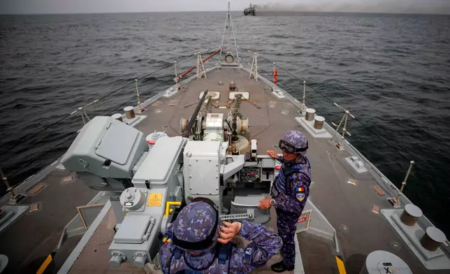 FILE - Romanian naval servicemen stand next to a gun onboard the M-270 Mine-hunter during a Romanian Navy led exercise outside Constanta, Romania, on April 16, 2024. (AP Photo/Andreea Alexandru, File)