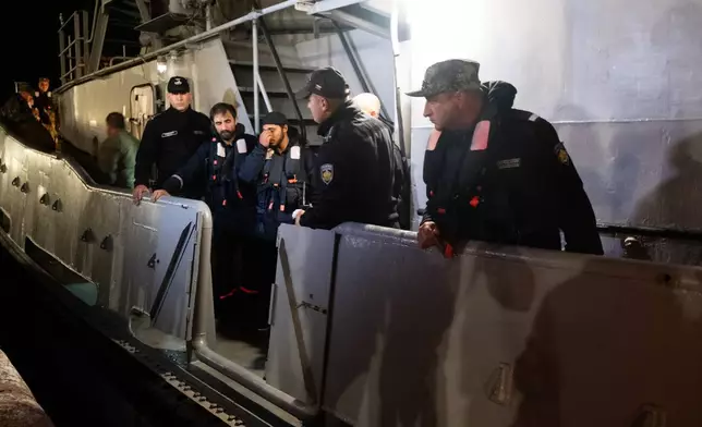 Four of the saved sailors from the drone-attacked and sunk ship HS Dignity seen on emergency rescue tug of Bulgarian Navy's - Mizar as they are transported to the port of Varna, Bulgaria, late Tuesday, Oct. 13, 2026. (Moreto.net via AP)