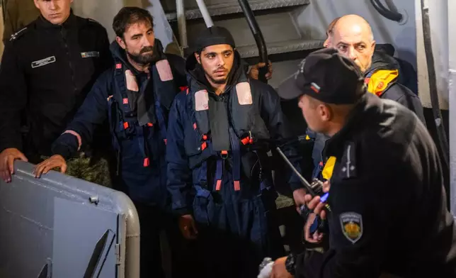 Four of the saved sailors from the drone-attacked and sunk ship HS Dignity seen on emergency rescue tug of Bulgarian Navy's - Mizar as they are transported to the port of Varna, Bulgaria, late Tuesday, Oct. 13, 2026. (Moreto.net via AP)