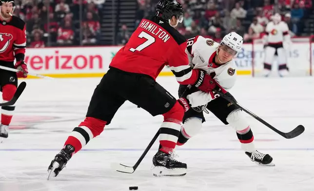Ottawa Senators' Tim Stützle, right, tries to pass around New Jersey Devils' Dougie Hamilton during the first period of an NHL hockey game in Newark, N.J., Monday, Oct. 12, 2026. (AP Photo/Seth Wenig)