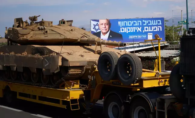 A tank mounted on a military truck passes an election campaign poster featuring Gadi Eisenkot, leader of the centrist Yashar ("Straight") party, ahead of Israel's general election in Kiryat Shmona, near the border with Lebanon in northern Israel, Tuesday, Oct. 20, 2026. (AP Photo/Ariel Schalit)