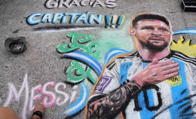 Street artist Claudio Pampillon finishes a chalk portrait of Lionel Messi on the pavement outside the stadium before Messi's final match with the national team, an international friendly against Benin in Buenos Aires, Argentina, Tuesday, Oct. 6, 2026. (AP Photo/Rodrigo Abd)