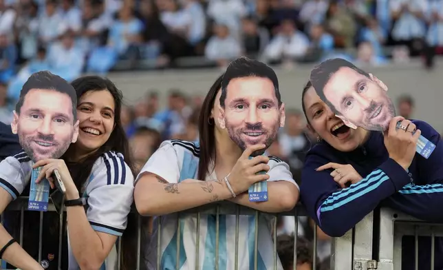 Fans hold masks depicting Lionel Messi before his final match for Argentina, a soccer friendly against Benin, in Buenos Aires, Argentina, Tuesday, Oct.6, 2026. (AP Photo/Natacha Pisarenko)