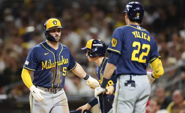 Milwaukee Brewers' Garrett Mitchell (5) is greeted by Christian Yelich (22) after scoring on a single by Jackson Chourio during the fifth inning in Game 4 of baseball's National League Division Series against the San Diego Padres Wednesday, Oct. 7, 2026, in San Diego. (AP Photo/Derrick Tuskan)