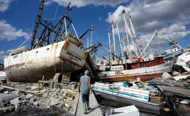 FILE - Bruce Hickey walks along the waterfront littered with debris and shrimp boats in the mobile home park where he and his wife Kathy have a winter home on San Carlos Island, Fort Myers Beach, Fla., Oct. 5, 2022, one week after the passage of Hurricane Ian. (AP Photo/Rebecca Blackwell, File)