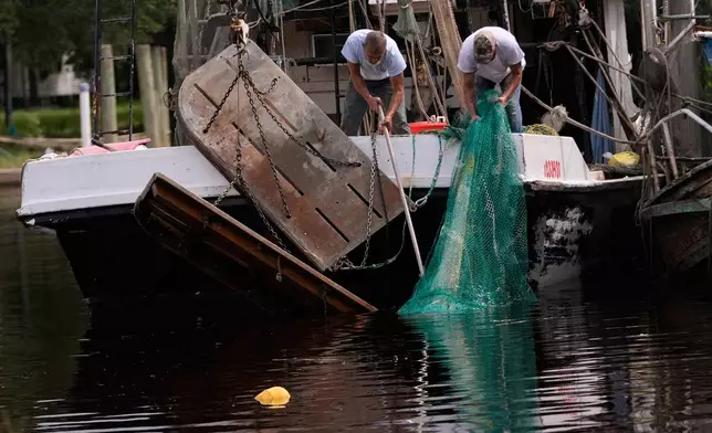 Boat owner Tony Rice, right, and his friend Lance Connor haul doors onto his boat to secure it as Hurricane Isaias approaches Bayou La Batre, Ala., Thursday, Oct. 8, 2026. (AP Photo/Gerald Herbert)