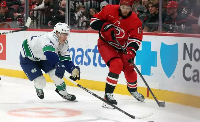 Carolina Hurricanes' K'andre Miller (19) clears the puck from Vancouver Canucks' Liam Ohgren, left, during the first period of an NHL hockey game in Raleigh, N.C., Thursday, Oct. 8, 2026. (AP Photo/Karl DeBlaker)