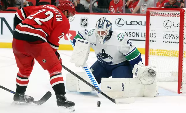 Carolina Hurricanes' Logan Stankoven (22) attempts to shoot the puck past Vancouver Canucks goaltender Kevin Lankinen, right, during the second period of an NHL hockey game in Raleigh, N.C., Thursday, Oct. 8, 2026. (AP Photo/Karl DeBlaker)