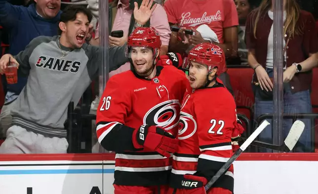 Carolina Hurricanes' Sean Walker (26) congratulates Logan Stankoven, right, on his goal during the second period of an NHL hockey game against the Vancouver Canucks in Raleigh, N.C., Thursday, Oct. 8, 2026. (AP Photo/Karl DeBlaker)