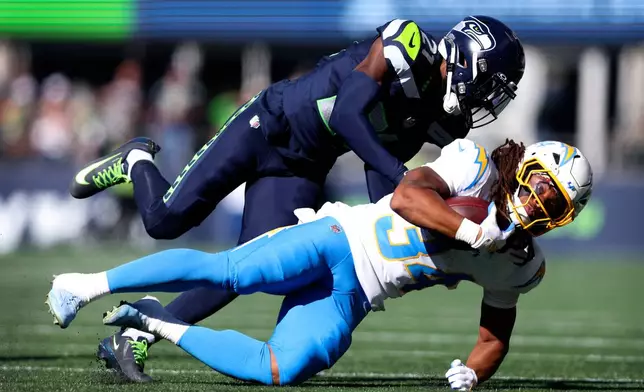 Los Angeles Chargers running back Keaton Mitchell (34) is tackled by Seattle Seahawks cornerback Devon Witherspoon (21) during the first half of an NFL football game, Sunday, Oct. 4, 2026, in Seattle. (AP Photo/Kevin Ng)