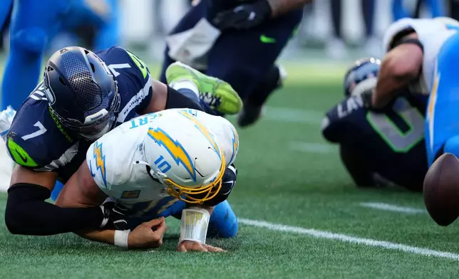 Los Angeles Chargers quarterback Justin Herbert (10) fumbles as he is tackled by Seattle Seahawks linebacker Uchenna Nwosu (7) during the second half of an NFL football game, Sunday, Oct. 4, 2026, in Seattle. (AP Photo/Lindsey Wasson)