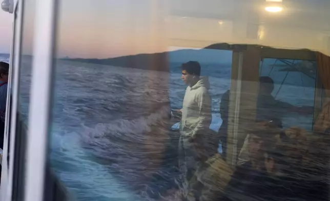 High school student Antonis Aivaliotis, 17, center, travels with other passengers by boat across the Ionian Sea from the island of Kalamos, where he lives, to school in the mainland town of Mytikas, western Greece, early Thursday, Sept. 24, 2026. (AP Photo/Petros Giannakouris)