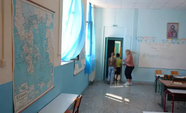 A map of Greece hangs on a wall as teacher Chryssa Ntalaka and her two sixth-grade students, the only students at Kalamos Primary School, leave their classroom on the island of Kalamos in the Ionian Sea, western Greece, Wednesday, Sept. 23, 2026. (AP Photo/Petros Giannakouris)