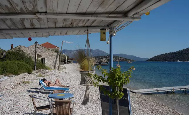A tourist sunbathes at Agrapidia Beach on the island of Kalamos in the Ionian Sea, western Greece, Wednesday, Sept. 23, 2026. (AP Photo/Petros Giannakouris)