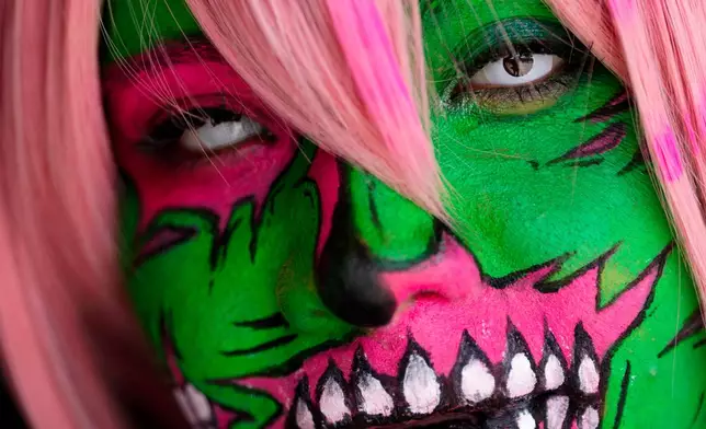 A woman eyes the camera while taking part in the Zombie Walk Retro 2026, a time-travel-themed march featuring costumes inspired by monsters and bygone eras, in Santiago, Chile, Saturday, Oct. 17, 2026. (AP Photo/Esteban Felix)