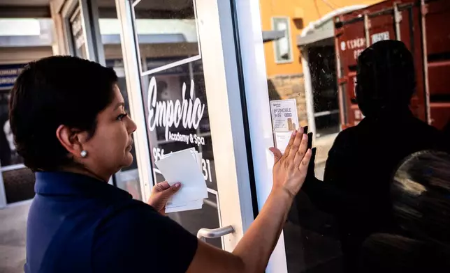 Cindy Banda leaves a flyer advertising Spectrum services near the door of Emporia Academy and Spa, Sept. 14, 2026, in McAllen, Texas. (AP Photo/Julia Demaree Nikhinson)