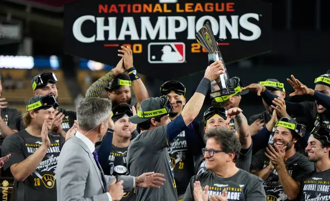Milwaukee Brewers designated hitter Christian Yelich holds the trophy as he celebrates with teammates after Game 4 of baseball's National League Championship Series between the Milwaukee Brewers and the Los Angeles Dodgers, Thursday, Oct. 15, 2026, in Los Angeles. (AP Photo/Ashley Landis)