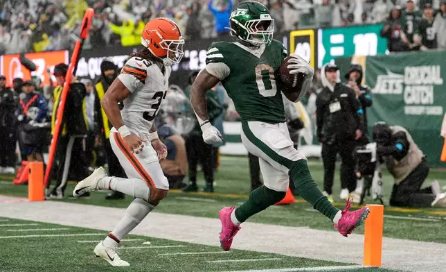 New York Jets running back Braelon Allen (0) scores a touchdown ahead of Cleveland Browns safety Ronnie Hickman (33) during the second half of an NFL football game, Sunday, Oct. 11, 2026, in East Rutherford, N.J. (AP Photo/Seth Wenig)